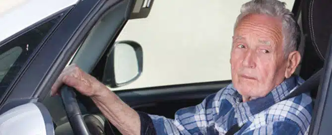 senior man driving a car looking out window